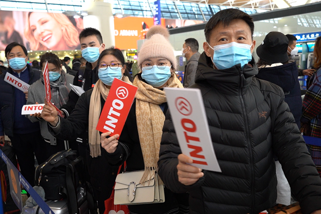 INTO Chinese students and their parents wearing face masks wait in line to check luggage in advance of charter flight to UK at Shanghai Pudong airport.